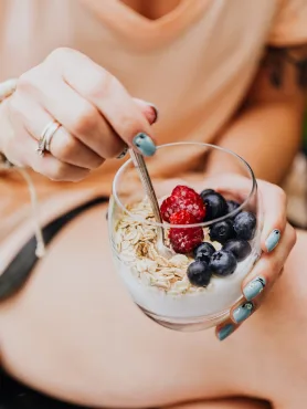 close up of woman holding a glass with yogurt oats and fruit